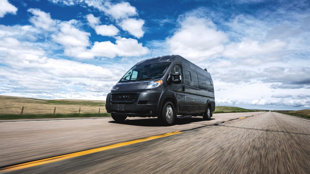 Airstream's Rangeline driving on a road with blue skies and clouds behind it. Airstream and RAM ProMaster® 3500 come together for the latest touring coach product launch.